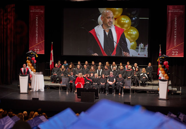 Photo of Toronto Film School President Andrew Barnsley giving is convocation address on stage at the TFS graduation